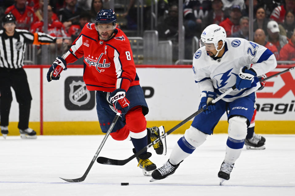 Washington Capitals left wing Alex Ovechkin (8) and Tampa Bay Lightning defenseman Matt Dumba (24) contend for control of the puck during the first period of an NHL hockey game Saturday, April 13, 2024, in Washington. (AP Photo/John McDonnell)