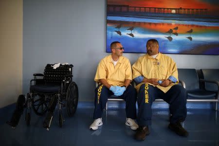 Gold Coat inmate workers who help other prisoners with health problems, Eleazar Ibarrola, 43, (L) and Scottie Glenn, 47, chat at the California Health Care Facility in Stockton, California, U.S., May 24, 2018. REUTERS/Lucy Nicholson