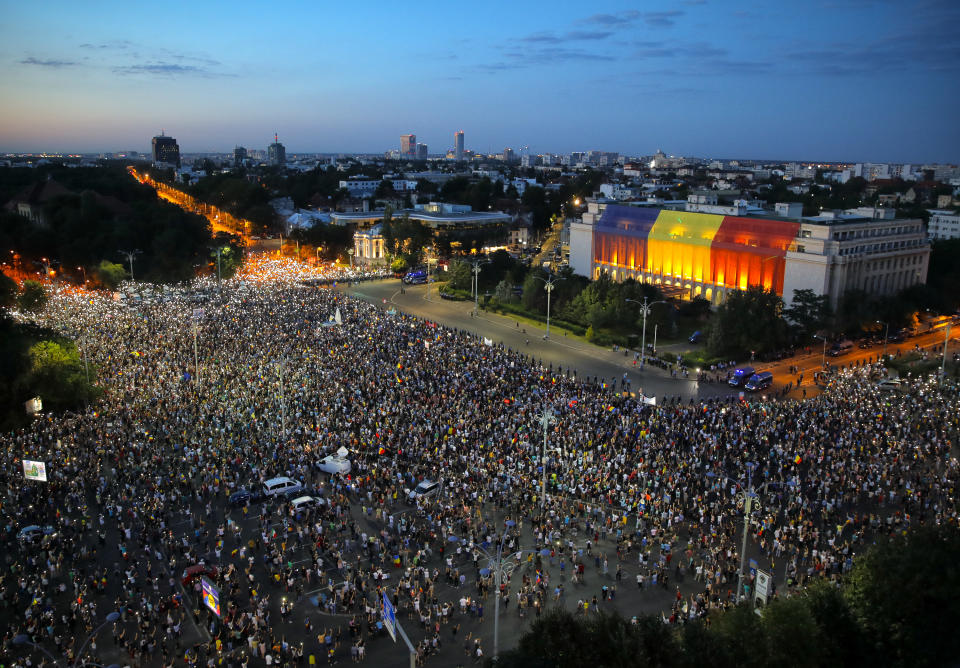 People shine the lights of their mobile phones during a protest outside the government headquarters, in Bucharest, Romania, Saturday, Aug. 11, 2018. Romanians gathered for a second day of protest Saturday, a day after an anti-government protest turned violent leaving 455 people, including three dozen riot police, needing medical treatment. (AP Photo/Vadim Ghirda)