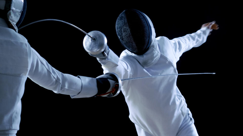 Two fencing athletes facing off against a black backdrop.