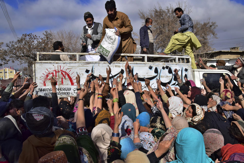 FILE - People jostle each other to buy subsidized sacks of wheat flour in Quetta, Pakistan, Thursday, Jan. 12, 2023, after a recent price hike of flour in the country. An Associated Press analysis of a dozen countries most indebted to China - including Pakistan, Kenya, Zambia and Laos - found the debt is consuming an ever-greater amount of tax revenue needed to keep schools open, provide electricity and pay for food and fuel. (AP Photo/Arshad Butt, File)