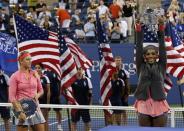 Serena Williams of the U.S. raises her trophy after defeating Victoria Azarenka of Belarus (L, holding runner up trophy) in their women's singles final match at the U.S. Open tennis championships in New York September 8, 2013. REUTERS/Mike Segar