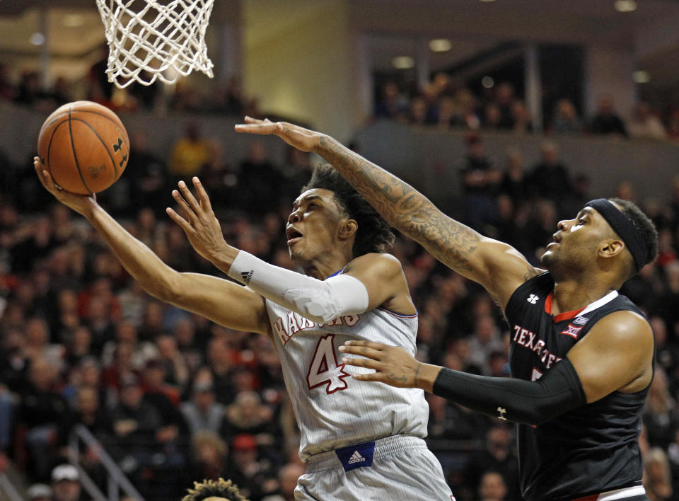 Kansas’ Devonte’ Graham (4) lays up the ball around Texas Tech’s Tommy Hamilton, right, during the second half of an NCAA college basketball game Saturday, Feb. 24, 2018, in Lubbock, Texas. (AP Photo/Brad Tollefson)