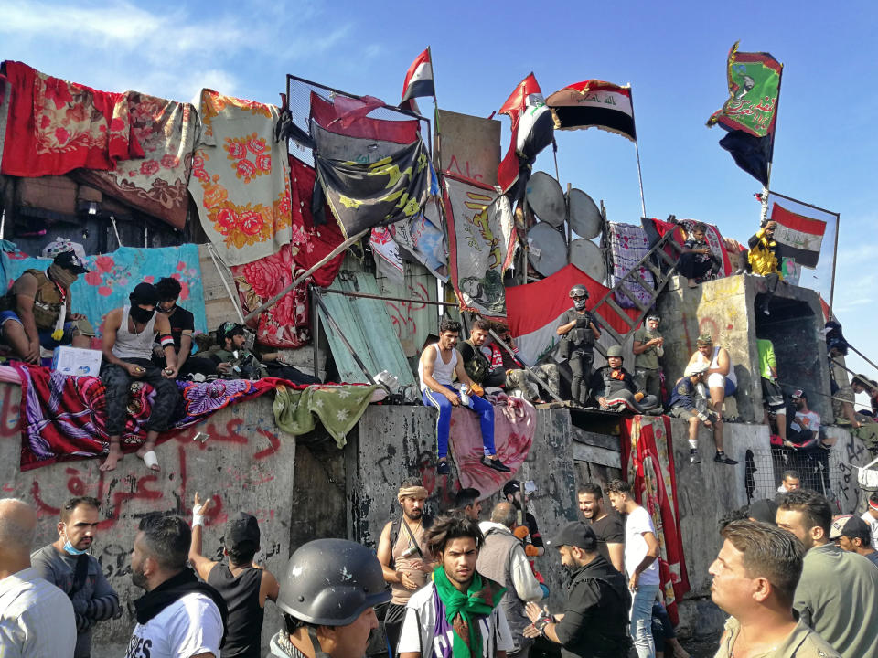 Manifestantes antigobierno están sobre barreras colocadas por las fuerzas de seguridad iraquíes para cerrar un puente que lleva a la Zona Verde de Bagdad, que alberga los edificios del gobierno y las embajadas, el jueves, 7 de noviembre del 2019. (AP Foto/Khalid Mohammed)