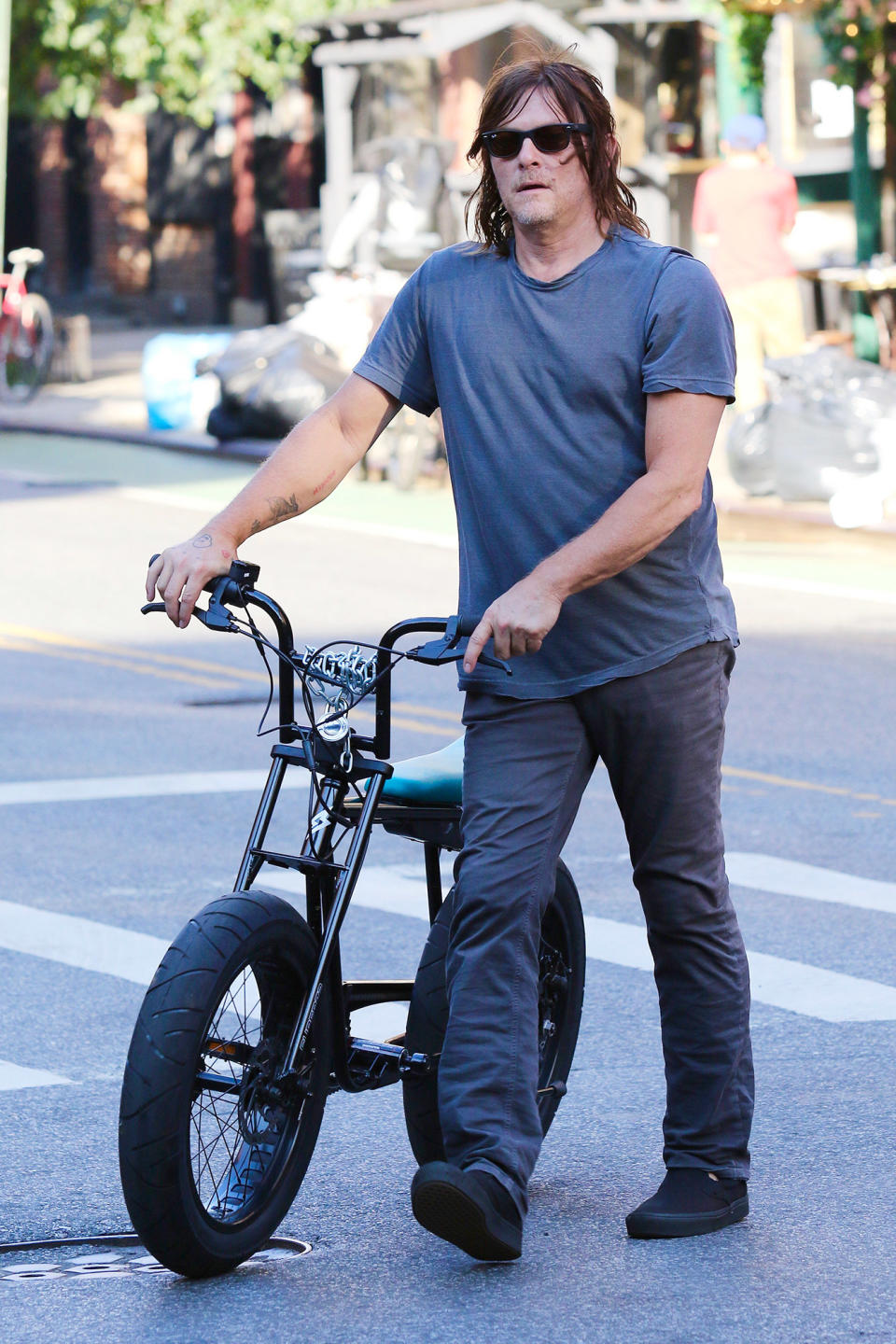 <p>Norman Reedus walks home after taking a bike ride through downtown N.Y.C. on July 31.</p>