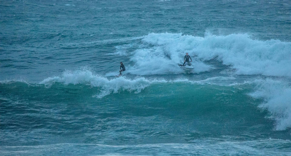 Surfer riding huge waves as wild wind hits the Sydney coastline Thursday evening.