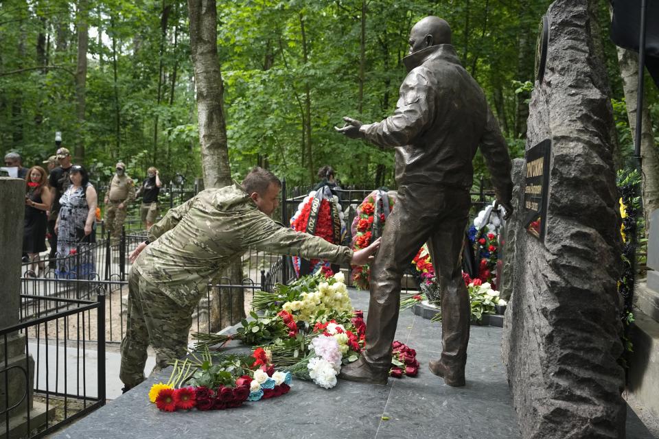 FILE - A fighter of the Wagner private military force touches a sculpture of Russian mercenary chief Yevgeny Prigozhin at his grave at the Porokhovskoye Cemetery in St. Petersburg, Russia, on Saturday, June 1, 2024. Prigozhin died in a suspicious air crash on Aug. 23, 2023, two months after launching a brief armed rebellion against the Russian military leadership. (AP Photo/Dmitri Lovetsky, File)