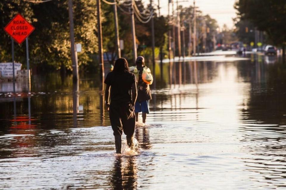 Residents walk down flooded streets after Hurricane Matthew caused downed trees, power outages, a municipal water outage and widespread flooding along the Lumber River Thursday, October 13, 2016 in Lumberton, NC.