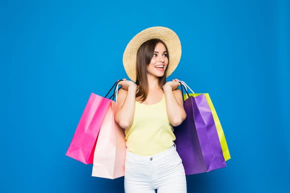 Woman carrying shopping bags against blue background.