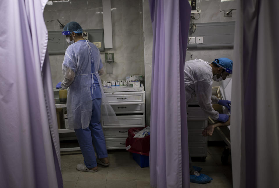 Palestinian doctors treat patients at the emergency room of the al-Quds Hospital in Gaza City, Monday, Sept. 7, 2020. Dozens of front-line health care workers have been infected, dealing a new blow to overburdened hospitals. (AP Photo/Khalil Hamra)