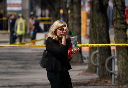 A pedestrian walks along a police crime scene tape near where a van struck multiple people at a major intersection in Toronto’s northern suburbs in Toronto