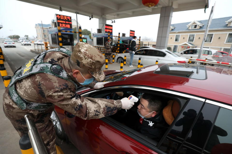 A militia member checks the body temperature of a driver on a vehicle at an expressway toll gate in Wuhan. Source: Getty