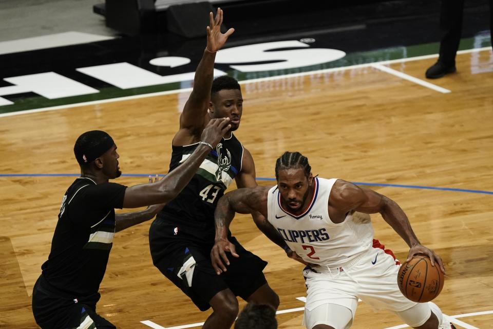 LA Clippers' Kawhi Leonard tries to drive past Milwaukee Bucks' Thanasis Antetokounmpo and Bobby Portis during the first half of an NBA basketball game Sunday, Feb. 28, 2021, in Milwaukee. (AP Photo/Morry Gash)