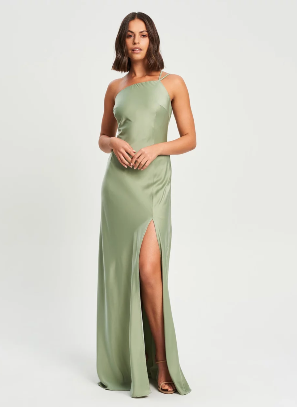 Woman with shoulder length hair wears a sage green maxi dress with one shoulder strap and thigh split. The Iconic CHANCERY Dusk Maxi Dress - $159.95