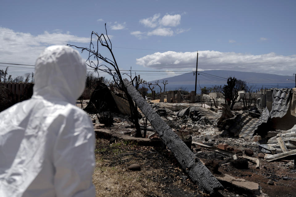 CORRECTS SPELLING OF LAST NAME TO VIERRA INSTEAD OF VERA - Leola Vierra looks at the remnants of her home for the first time, Tuesday, Sept. 26, 2023, in Lahaina, Hawaii. The Vierras are among the couple dozen residents who are able to return to their property in Zone 1-C following August's deadly wildfire. Authorities in Maui strongly encouraged homeowners to wear protective gear provided by nonprofit groups when visiting their properties to protect against asbestos, lead and other toxic remains of the wildfire. (AP Photo/Mengshin Lin)