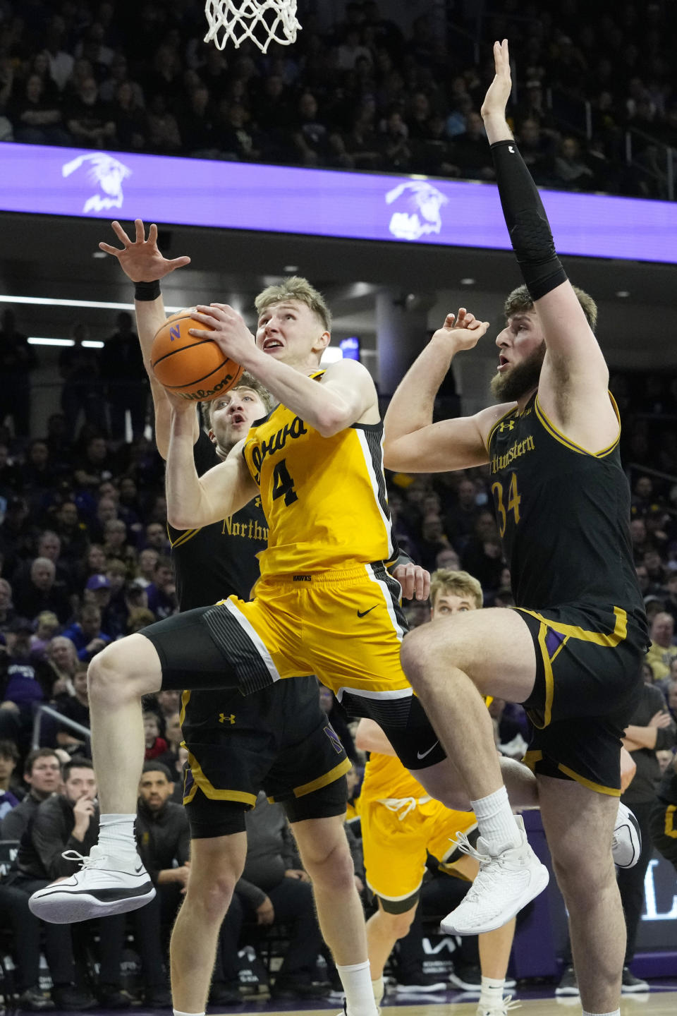 Iowa guard Josh Dix (4) drives to the basket against Northwestern forward Nick Martinelli, left, and center Matthew Nicholson during the first half of an NCAA college basketball game in Evanston, Ill., Saturday, March 2, 2024. (AP Photo/Nam Y. Huh)