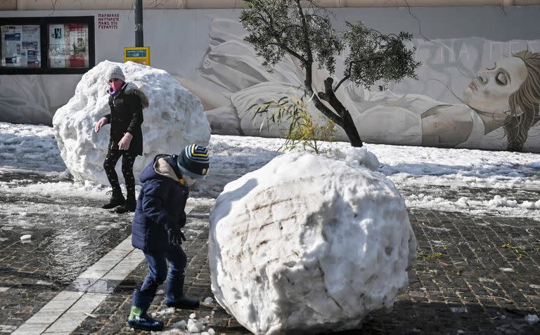 Los niños juegan con enormes bolas de nieve en Atenas el 25 de enero de 2022, después de una tormenta de nieve que interrumpió el tráfico en la capital griega