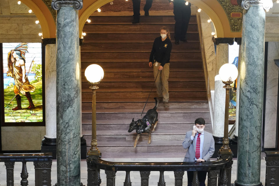 Deputy State Fire Marshal Kayla Riggs follows the agency's explosive detection dog, "Ringo," as he walks down the steps of the third floor at the Capitol in Jackson, Miss., Thursday, Jan. 14, 2021. State capitols across the country are under heightened security after the siege of the U.S. Capitol last week. The FBI has warned of plans for armed protests at all 50 state capitals ahead of President-elect Joe Biden's inauguration. (AP Photo/Rogelio V. Solis)