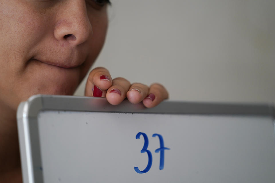 Gabriela Fajardo, a 26-year-old Honduran seeking asylum in the United States, teaches a Zoom class for Central American children living in camps, various shelters and apartments in other parts of Mexico on Friday, Nov. 20, 2020, from a hallway of an aged building in Matamoros, Mexico. Like countless schools, the sidewalk school, as it became known, went to virtual learning amid the coronavirus pandemic, but instead of being hampered by the change, it has blossomed. (AP Photo/Eric Gay)