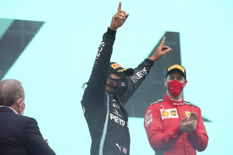 Third placed Ferrari driver Sebastian Vettel of Germany, right, applauds as Mercedes driver Lewis Hamilton of Britain celebrates after winning the Formula One Turkish Grand Prix at the Istanbul Park circuit racetrack in Istanbul, Sunday, Nov. 15, 2020. (Tolga Bozoglu/Pool via AP)