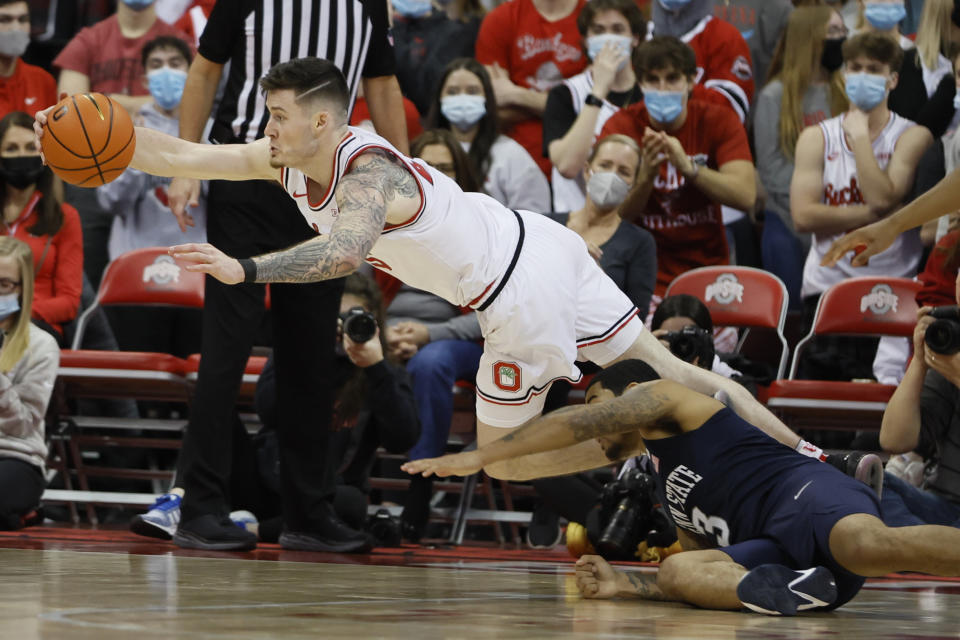 Ohio State's Kyle Young, left, saves a ball from going out of bounds as Penn State's Sam Sessoms defends during the second half of an NCAA college basketball game Sunday, Jan. 16, 2022, in Columbus, Ohio. (AP Photo/Jay LaPrete)