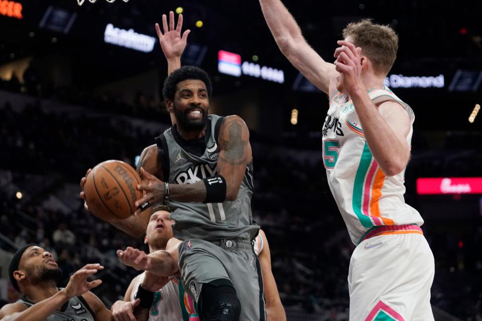 Brooklyn Nets guard Kyrie Irving (11) drives to the basket against San Antonio Spurs center Jakob Poeltl (25) during the first half of an NBA basketball game Friday, Jan. 21, 2022, in San Antonio. (AP Photo/Eric Gay)