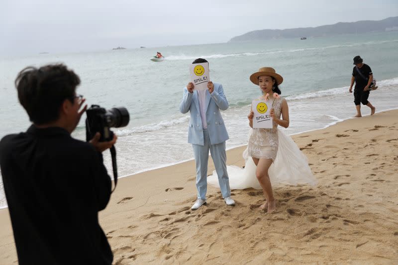 FILE PHOTO: A couple poses for pictures during a wedding photoshoot session on Yalong Bay beach in Sanya