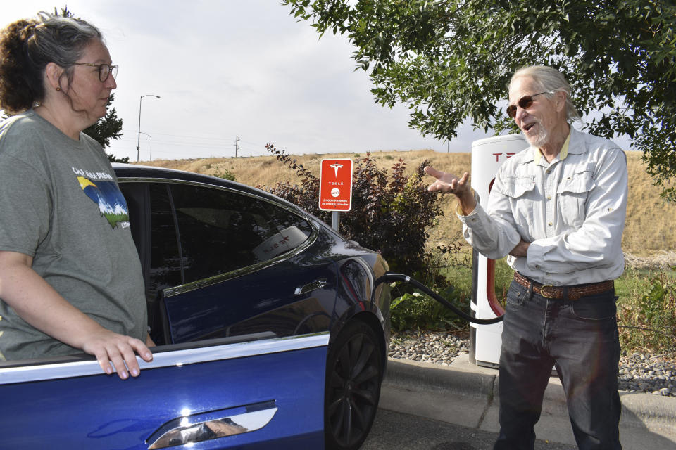 Jeannette Englehart of Billings, Mont. (left) stands outside her car speaking with fellow electric vehicle owner Bob Palrud of Spokane, Wash. at a charging station near Interstate 90, on Wednesday Sept. 14, 2022, in Billings, Mont. Officials from rural states in the U.S. west are pushing the Biden administration to ease requirements for charging stations because of limited demand in areas with low population densities. (AP Photo/Matthew Brown)