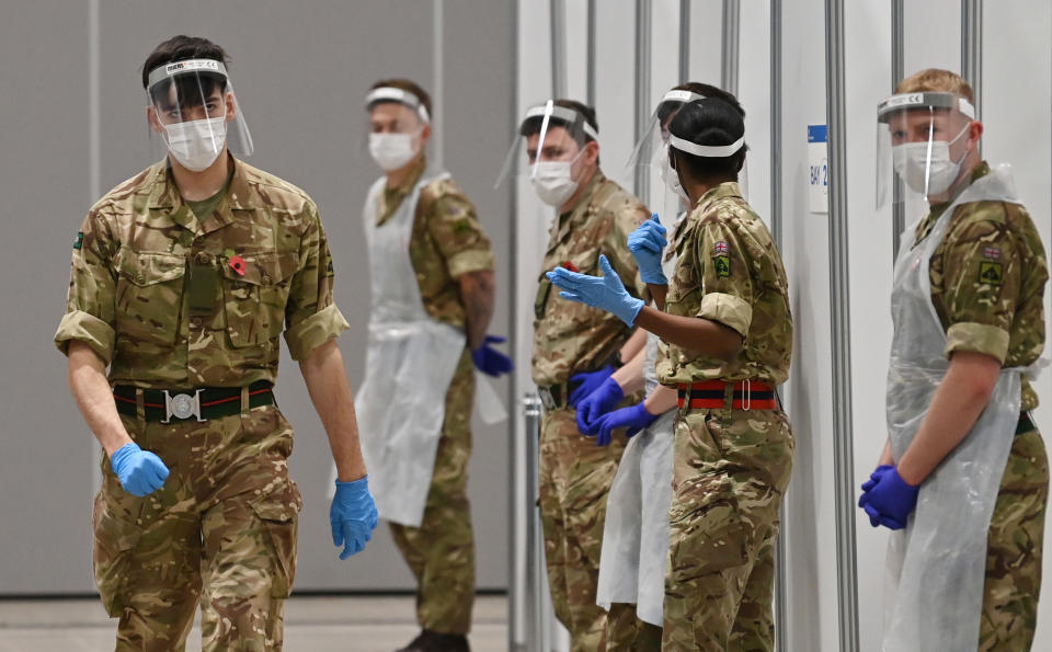 Soldiers wearing full PPE (personal protective equipment) in the form of face shields, gloves, face masks and bibs wait to assist covid testing at a coronavirus rapid testing centre in the Liverpool exhibition centre in Liverpool, north-west England on November 11, 2020, during a city-wide mass testing pilot operation. - Liverpool on November 6 began England's first city-wide trial of coronavirus testing in an attempt to prevent hospitals becoming overwhelmed during the country's second wave of the pandemic. All of the northwestern city's 500,000 residents as well as people working there will be offered repeat tests, even if asymptomatic, under the pilot trial, which will initially run for two weeks. (Photo by Paul ELLIS / AFP) (Photo by PAUL ELLIS/AFP via Getty Images)