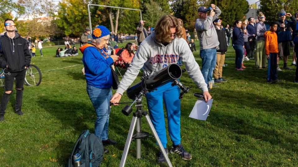 Boise State freshman Hunter Gregory, 19, of Boise, uses a telescope to reflect an image of the annular solar eclipse onto a sheet of paper at Boise State University, Saturday, Oct. 14, 2023. Boise State Physics’ Central Idaho Dark Sky Reserve STEM Network hosted an eclipse watch event at the Student Union Intramural Field.