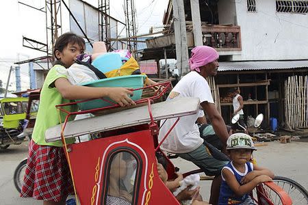 Residents with their belongings ride on a tricycle cab to an evacuation center in Tacloban city, central Philippines December 4, 2014. REUTERS/Stringer