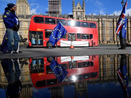 FILE PHOTO: Anti-Brexit demonstrators waving EU and Union flags are reflected in a puddle in front of the Houses of Parliament in London