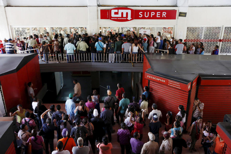 People wait to try to buy basic food items outside a supermarket in Caracas on April 22, 2016.