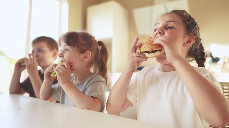 three kids eating burgers