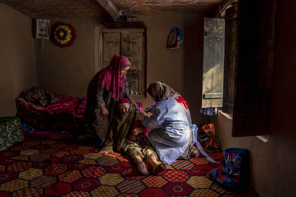 Arsha Begum recibe la vacuna Covishield para COVID-19 de parte de la trabajadora de la salud Fozia, durante una campaña de vacunación en Budgam, al suroeste de Srinagar, en la Cachemira india, el 11 de enero de 2022. (AP Foto/Dar Yasin)