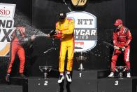 Alex Palou, center, of Spain, celebrates after winning the IndyCar Grand Prix auto race at Indianapolis Motor Speedway, Saturday, May 11, 2024, in Indianapolis. Will Power, left, of Australia, finished second, and Christian Lundgaard, of Denmark, finished third. (AP Photo/Darron Cummings)
