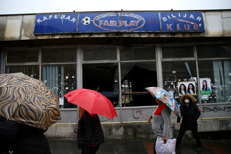 People pass by a closed cafe bar and betting outlet in Brcko, Bosnia and Herzegovina