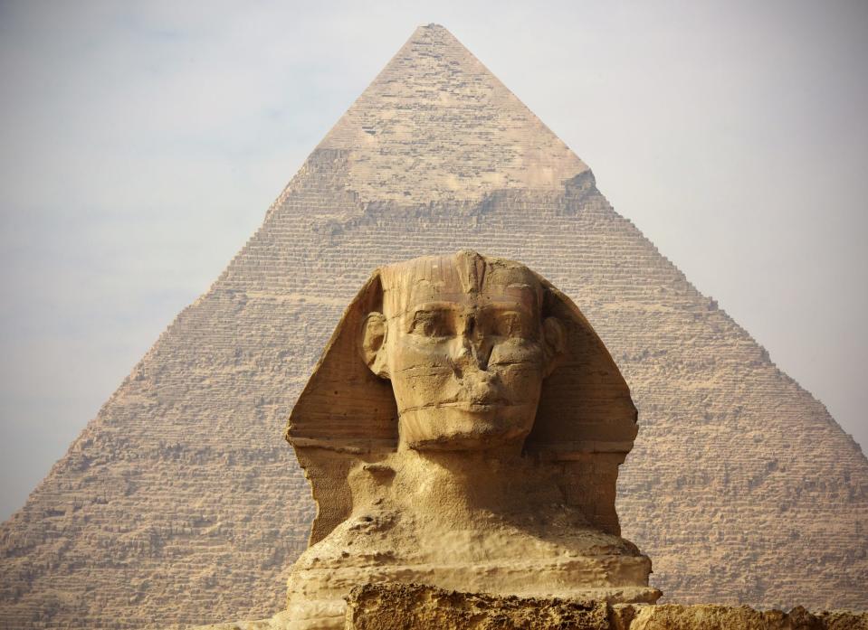The sphinx is shown in fron of the pyramid which towers over it.