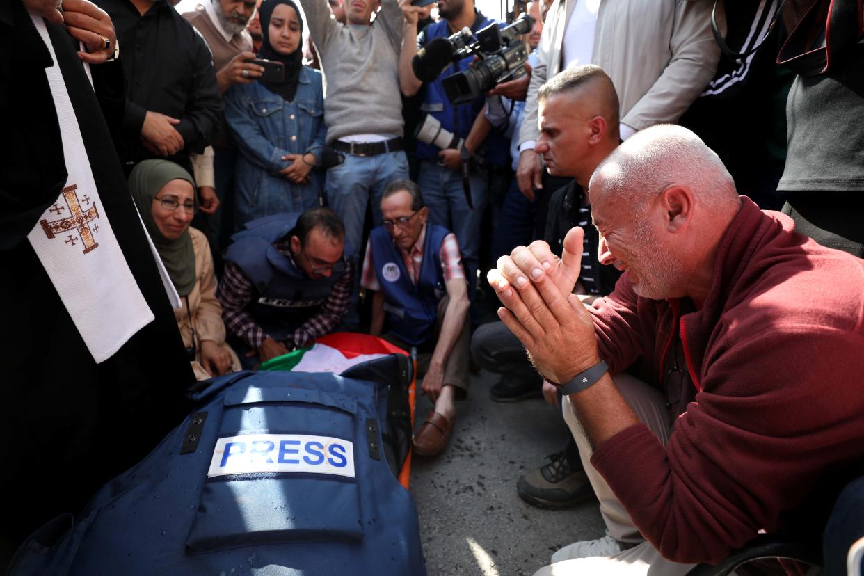 People mourn as they gather around the body of Shireen Abu Akleh. 