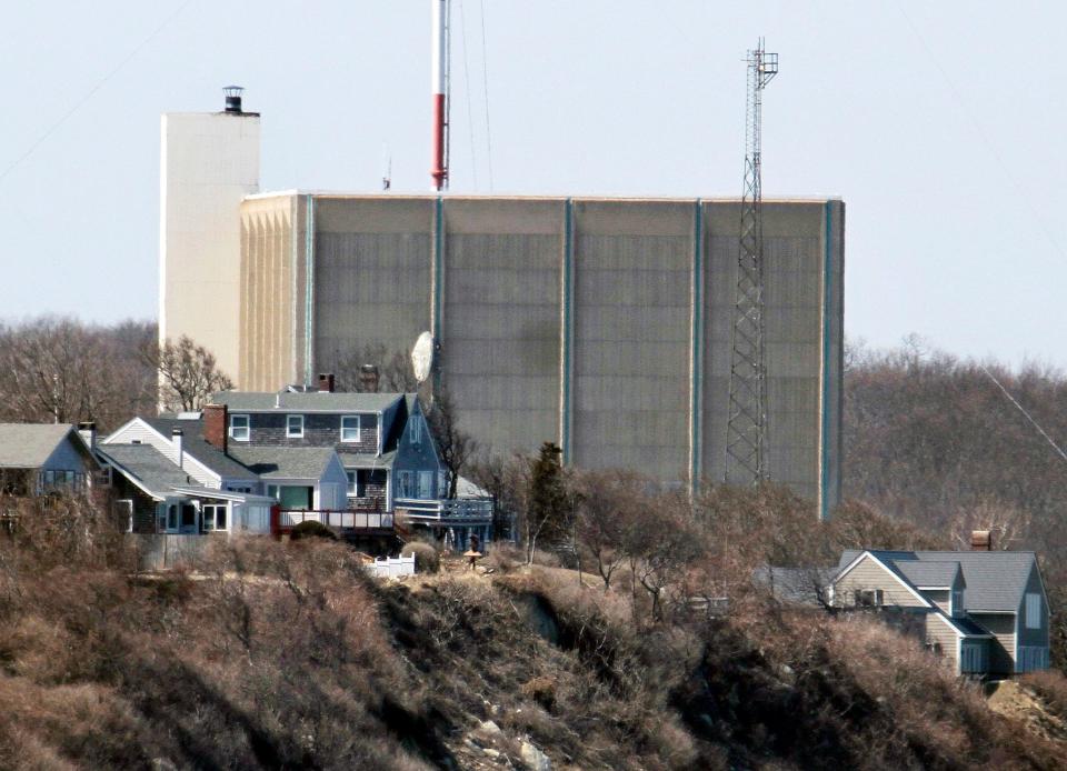 A portion of the Pilgrim Nuclear Power Station sits beyond houses along the coast of Cape Cod Bay in Plymouth, Mass.