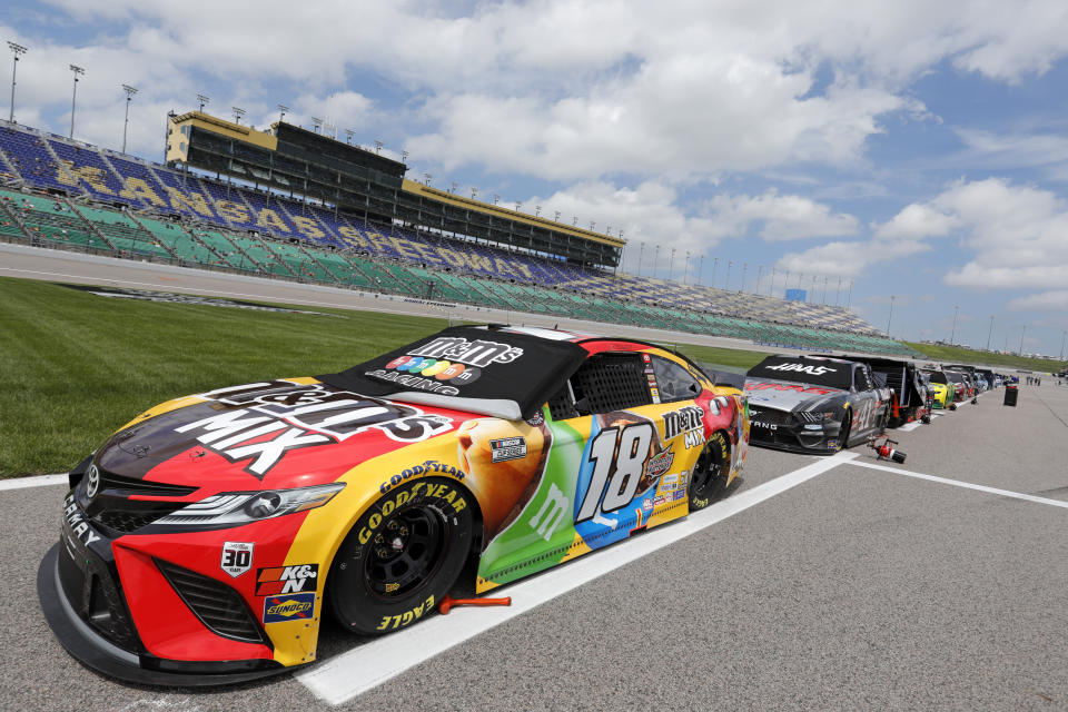 Kyle Busch's 18 car and others are parked along pit road before the start of a NASCAR Cup Series auto race at Kansas Speedway in Kansas City, Kan., Sunday, May 2, 2021. (AP Photo/Colin E. Braley)