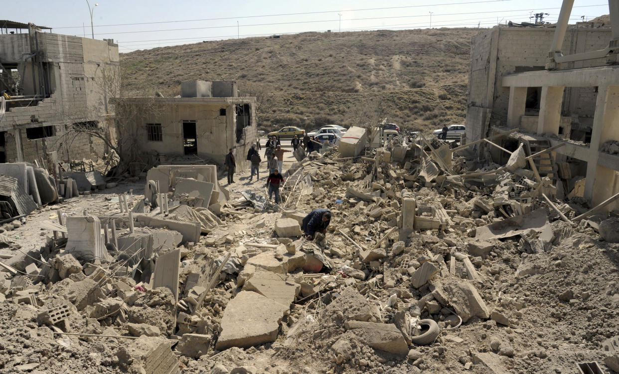 In this photo released by the Syrian official news agency SANA, people inspect damage after an Israeli airstrike near Damascus, Syria, Monday, March 7, 2022. Israel fired several missiles toward Syrian military positions near the capital Damascus Monday, killing two civilians and causing material damage, Syria's defense ministry said. It was the first Israeli attack inside Syria since Russia, a key backer of President Bashar Assad, invaded Ukraine. (SANA via AP)