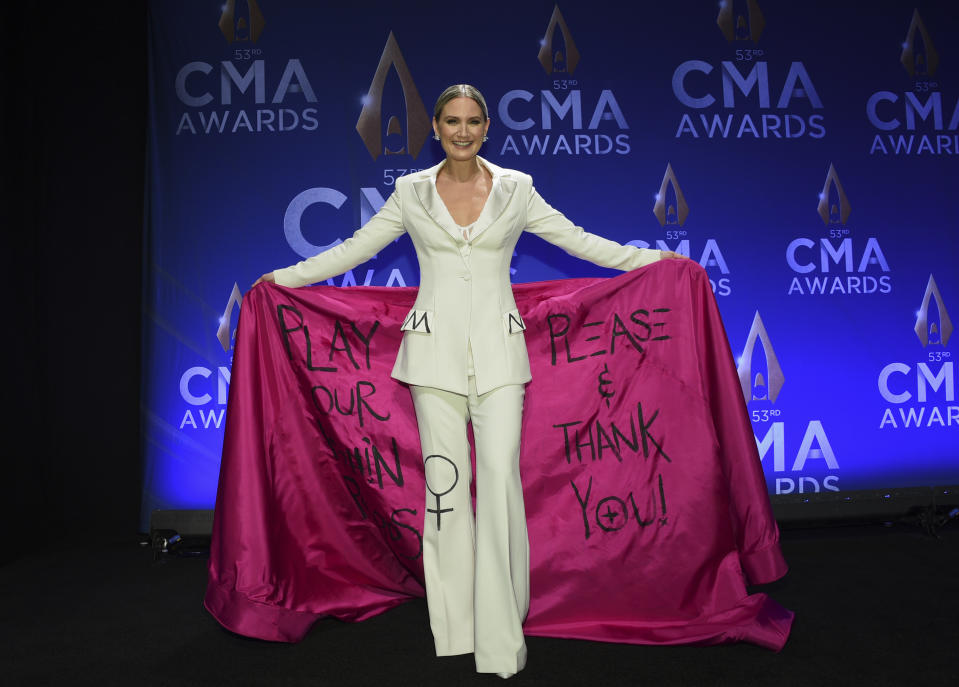 FILE - This Nov. 13, 2019 file photo shows singer-actress Jennifer Nettles wearing an outfit with wording asking radio stations to play more songs by women at the 53rd annual CMA Awards in Nashville, Tenn. What started as a joke on Twitter about an unwritten rule among country radio stations not to play two female artists in a row prompted outrage by country music stars, but also pledges to give women equal airtime. CMT announced on Tuesday, Jan. 21, 2020, that they would institute equal airplay for female artists across their two channels. And a country radio station in Ontario, Canada, started an equal play initiative for one week, pledging to split the airplay time 50-50 between men and female voices. (Photo by Evan Agostini/Invision/AP, File )