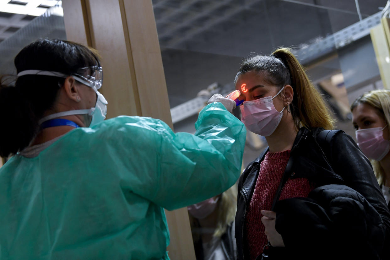 Airport staff check the temperatures of passengers returning from Milan as part of the coronavirus screening procedure at the Debrecen airport, Hungary, Tuesday, Feb. 25, 2020. The precautionary measures were introduced following the report of over 200 confirmed cases of COVID-19 disease and at least seven deaths in northern Italy. The first Hungarian diagnosed with coronavirus had been working on the Diamond Princess cruise ship quarantined in Japan. (Zsolt Czeglédi/MTI via AP)