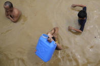 A resident goes out to buy drinking water as he negotiates a flooded road from Typhoon Noru in San Miguel town, Bulacan province, Philippines, Monday, Sept. 26, 2022. Typhoon Noru blew out of the northern Philippines on Monday, leaving some people dead, causing floods and power outages and forcing officials to suspend classes and government work in the capital and outlying provinces. (AP Photo/Aaron Favila)