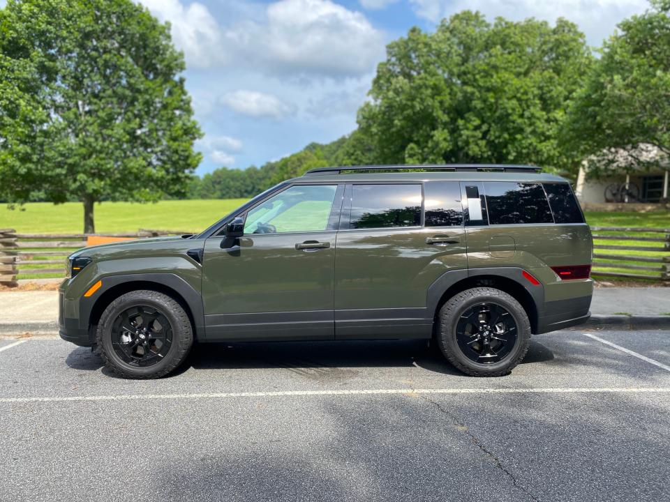 The side of a green 2024 Hyundai Santa Fe XRT SUV that's parked at a park.