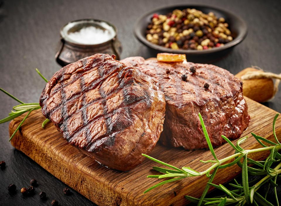 Two beef steaks sitting on wooden tray.