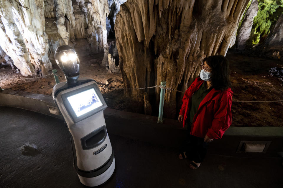 A guide programs Persephone inside Alistrati cave, about 135 kilometers (84 miles) northeast of Thessaloniki, Greece, Monday, Aug. 2, 2021. Persephone, billed as the world's first robot used as a tour guide inside a cave, has been welcoming visitors to the Alistrati cave, since mid-July. (AP Photo/Giannis Papanikos)