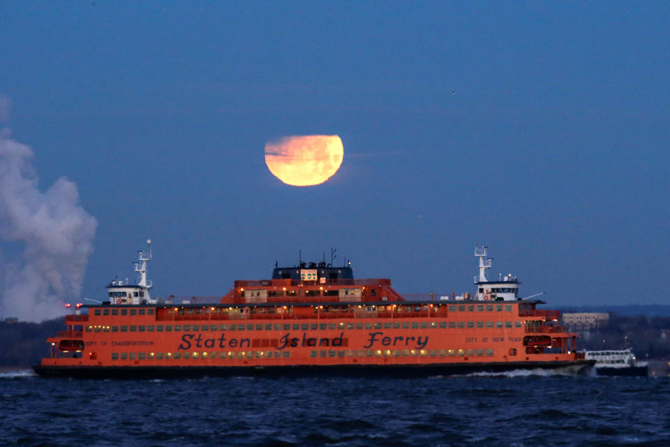 The&nbsp;moon sets behind the Staten Island Ferry, seen from Brooklyn.