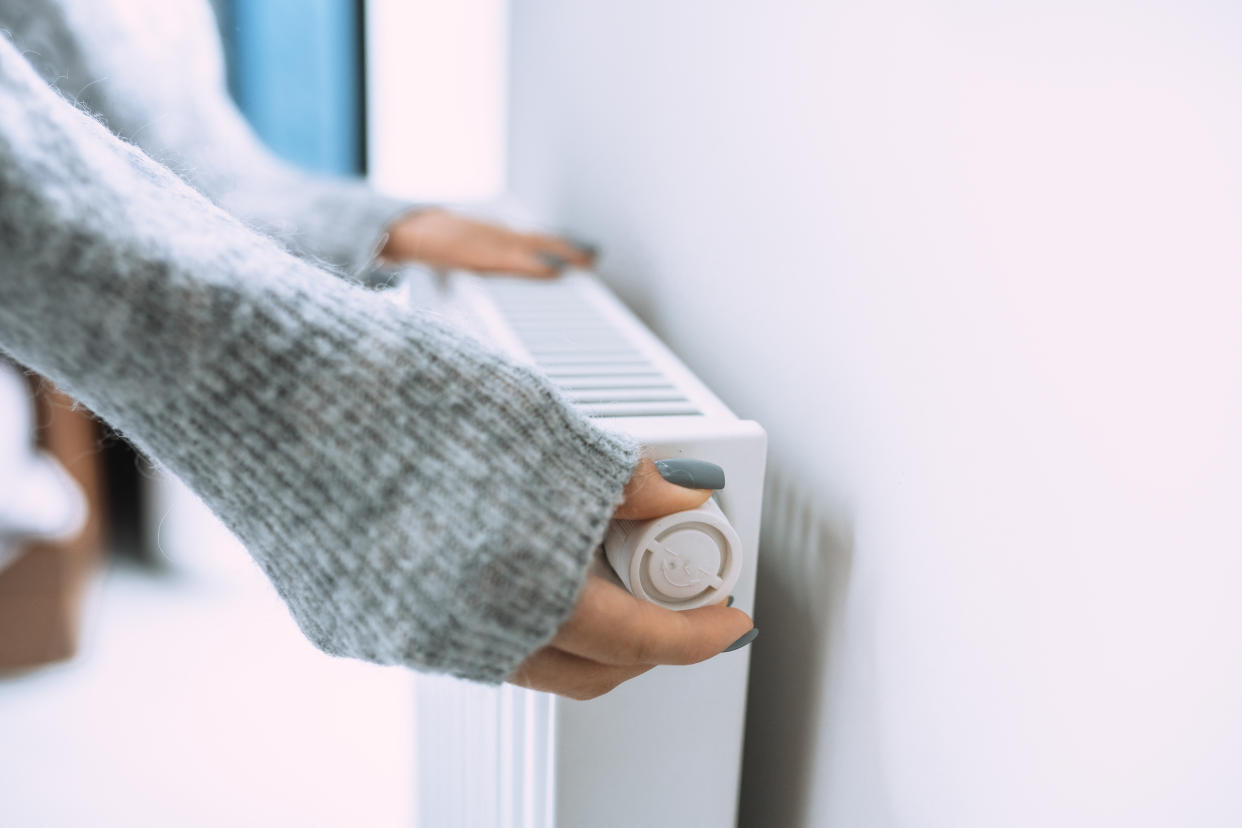 Unrecognizable woman hands in gray sweater touching and setting radiator thermostat regulator